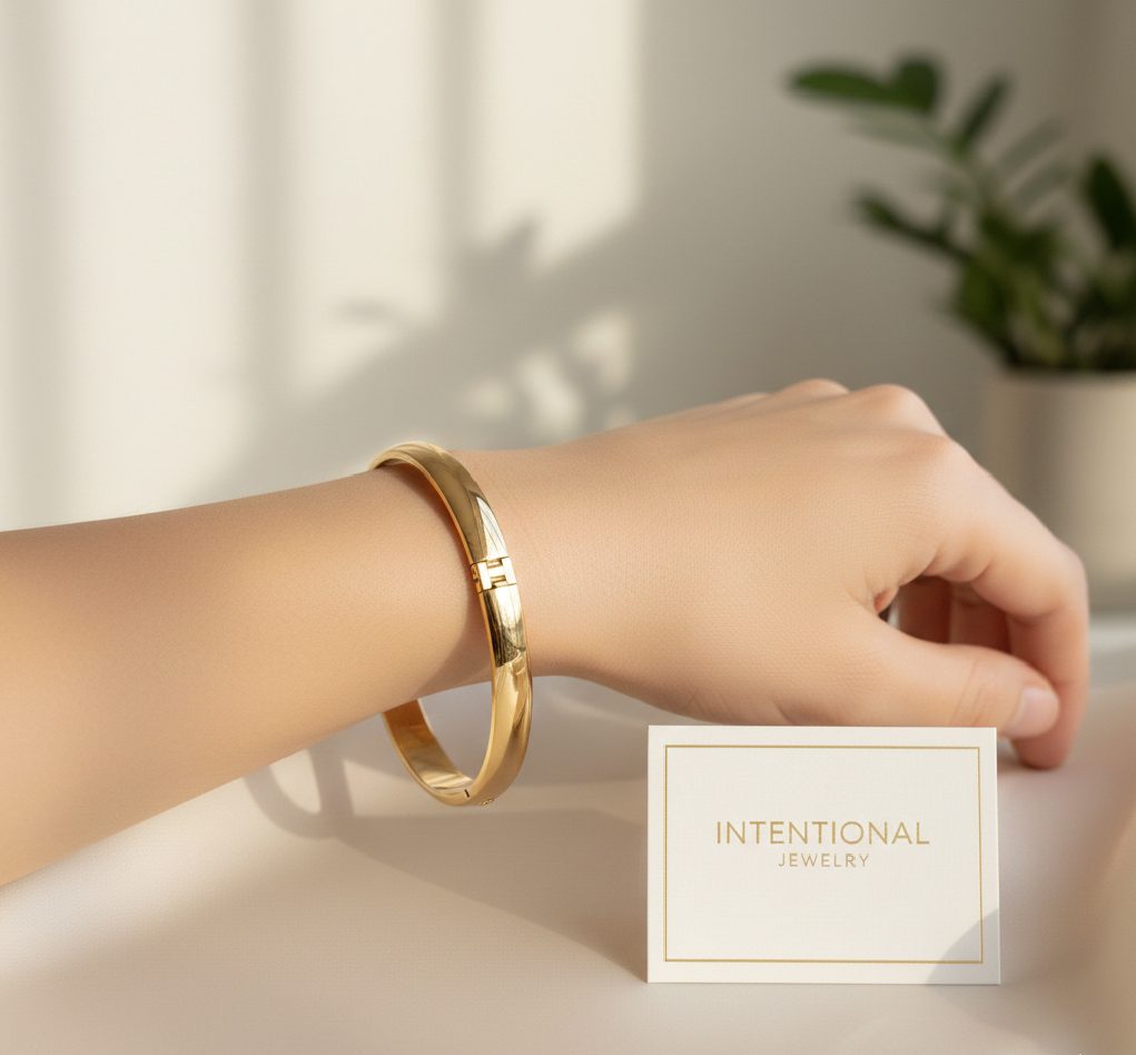 A structured, high-shine gold bangle bracelet with a hinged design, inspired by iconic luxury jewelry styles.